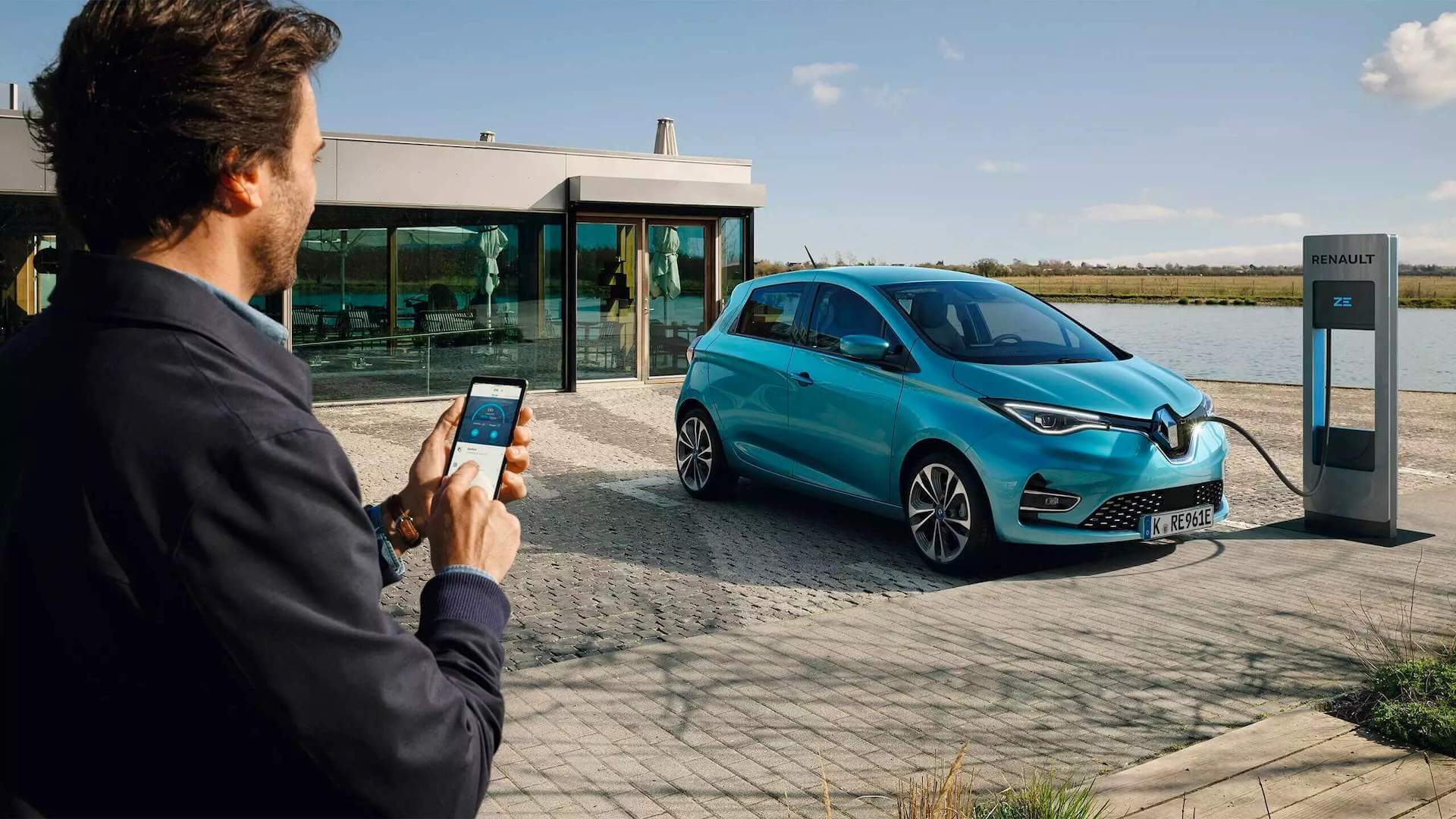 Renault Zoe türkis - Seitenansicht - Auto wird an eine Elektrotankstelle per Smartphone von einem Mann geladen - Renault Ahrens Hannover